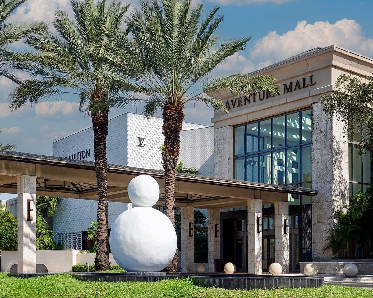 Entrance to Aventura Mall with palm trees and a sculpture, a luxury shopping landmark in Aventura, Florida