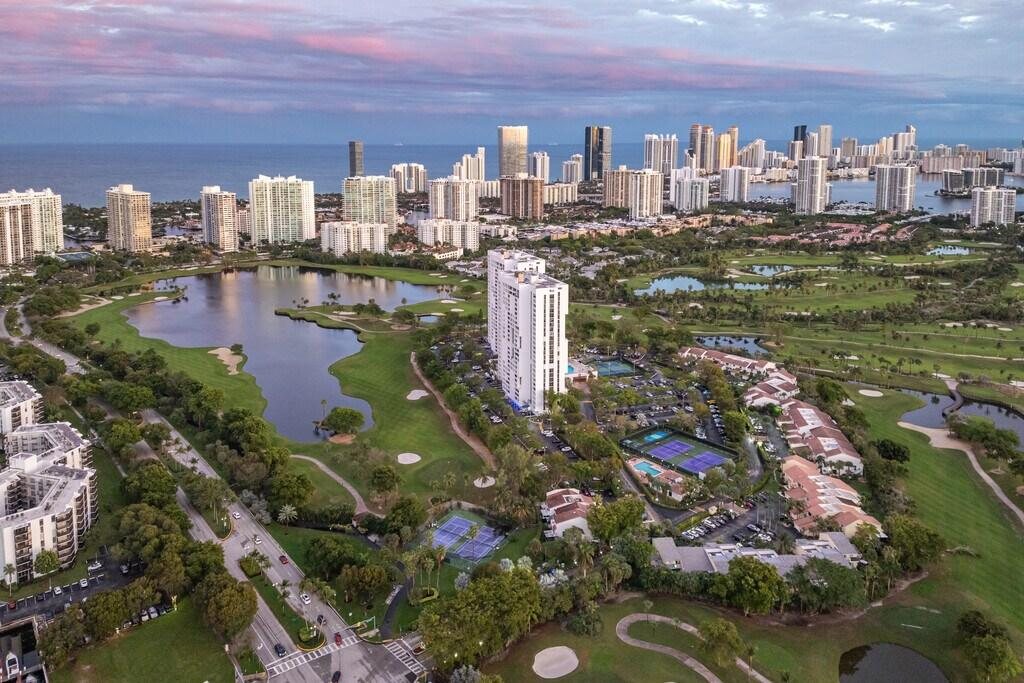 Aerial view of the Turnberry golf course and country-club residences in Aventura, Florida, with high-rise towers and the ocean beyond at dusk
