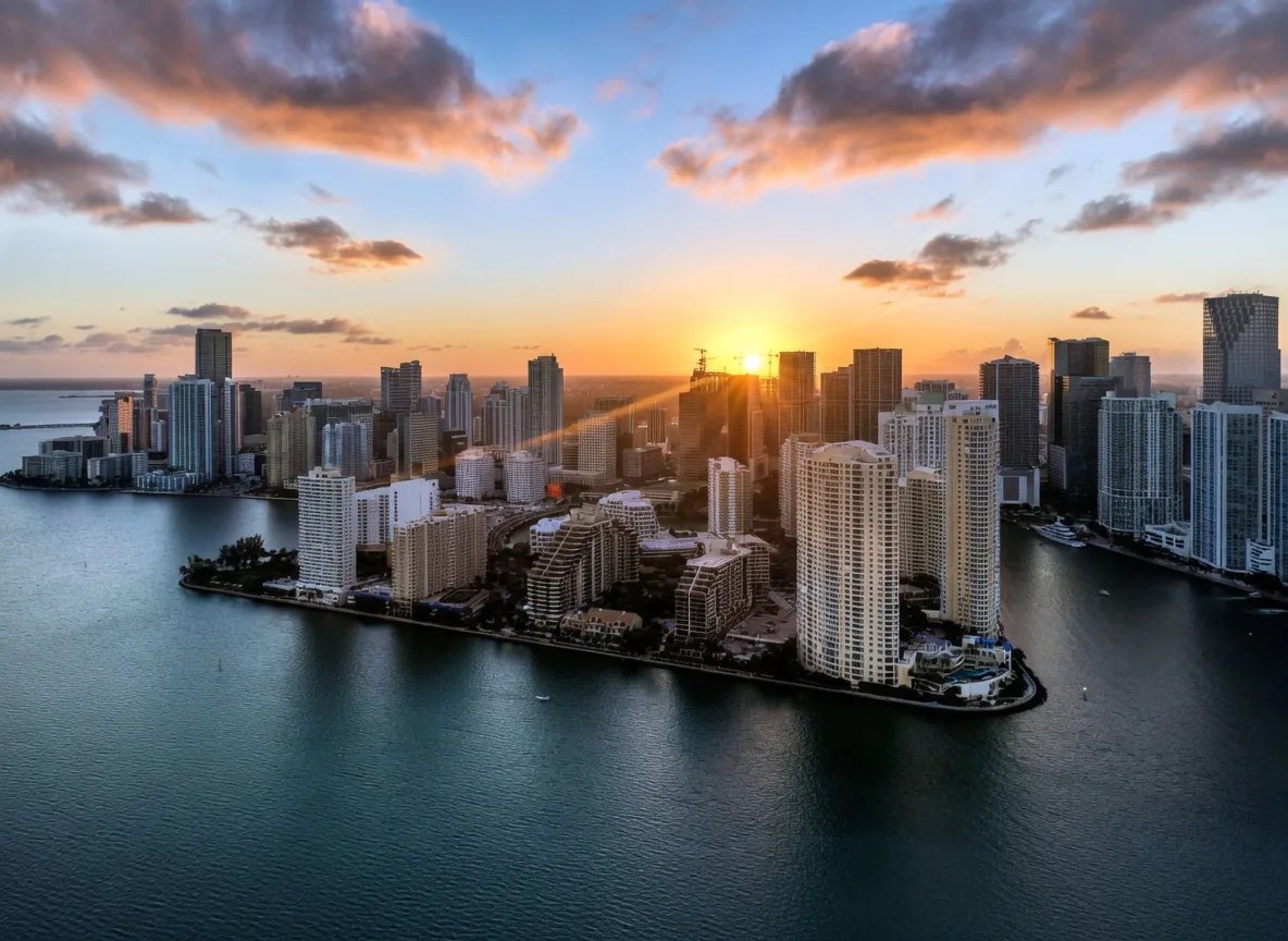 Vista a&eacute;rea al atardecer de las torres residenciales frente al agua de Brickell Key con el horizonte de Brickell en Miami