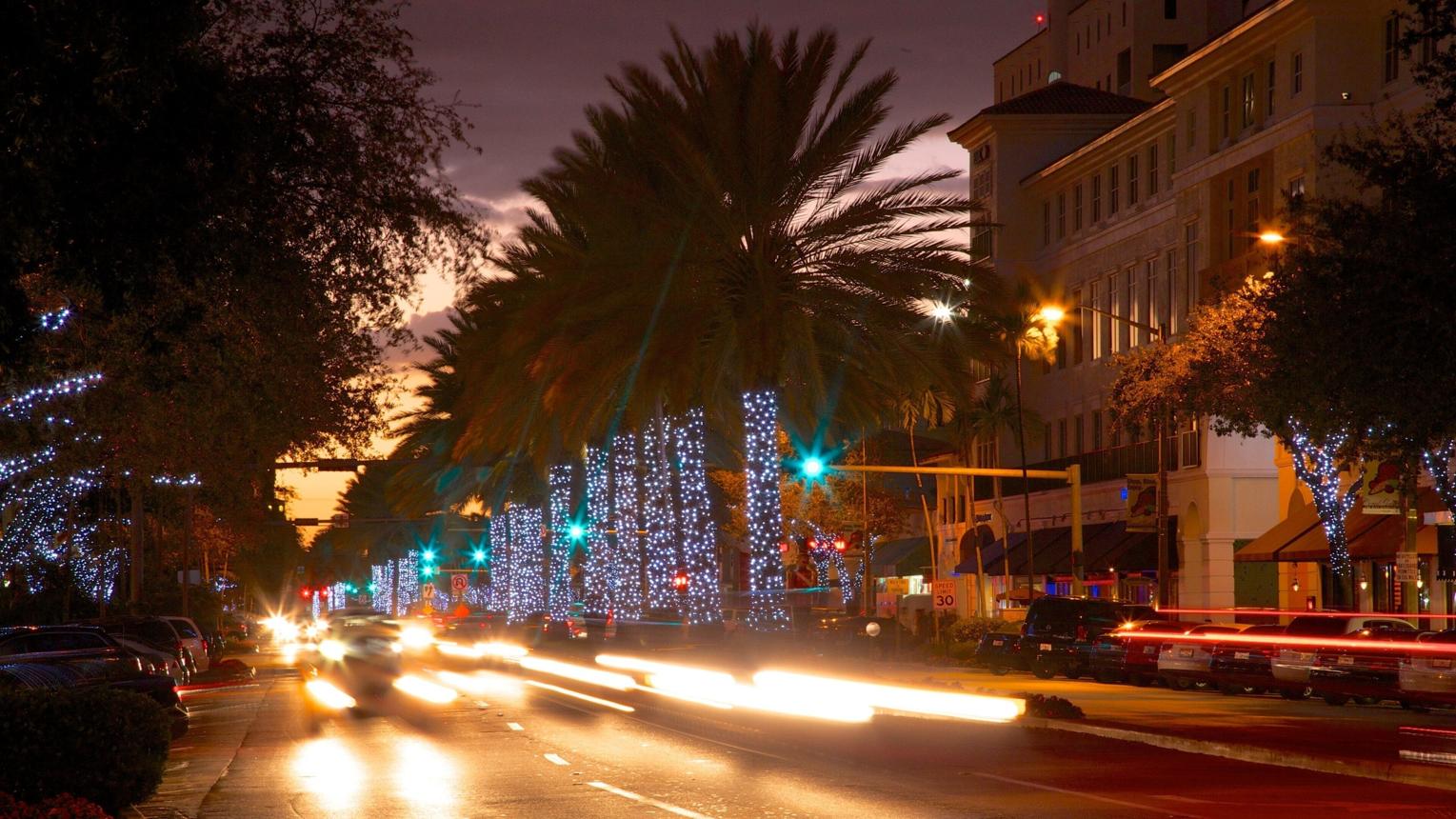Miracle Mile in Coral Gables at night, lined with palm trees and lit storefronts near Cassia Residences