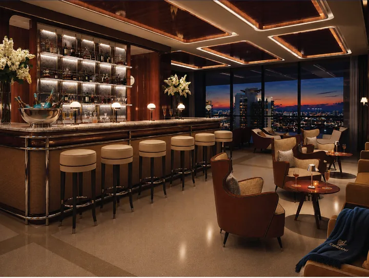 Imagen ilustrativa de un sal&oacute;n estilo speakeasy con una larga barra de madera y lat&oacute;n y sillones frente a una vista del horizonte de Miami al anochecer
