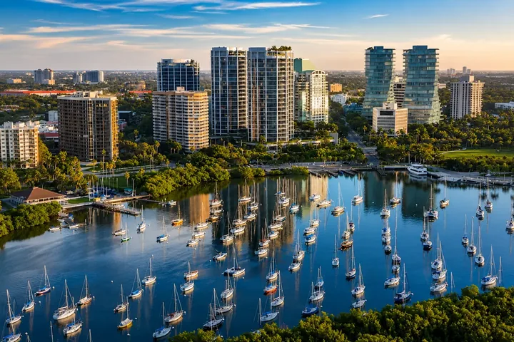 Vista aérea de Coconut Grove, Miami, con veleros fondeados frente a Dinner Key, la arboleda del pueblo y las torres de condominios frente a la bahía sobre South Bayshore Drive