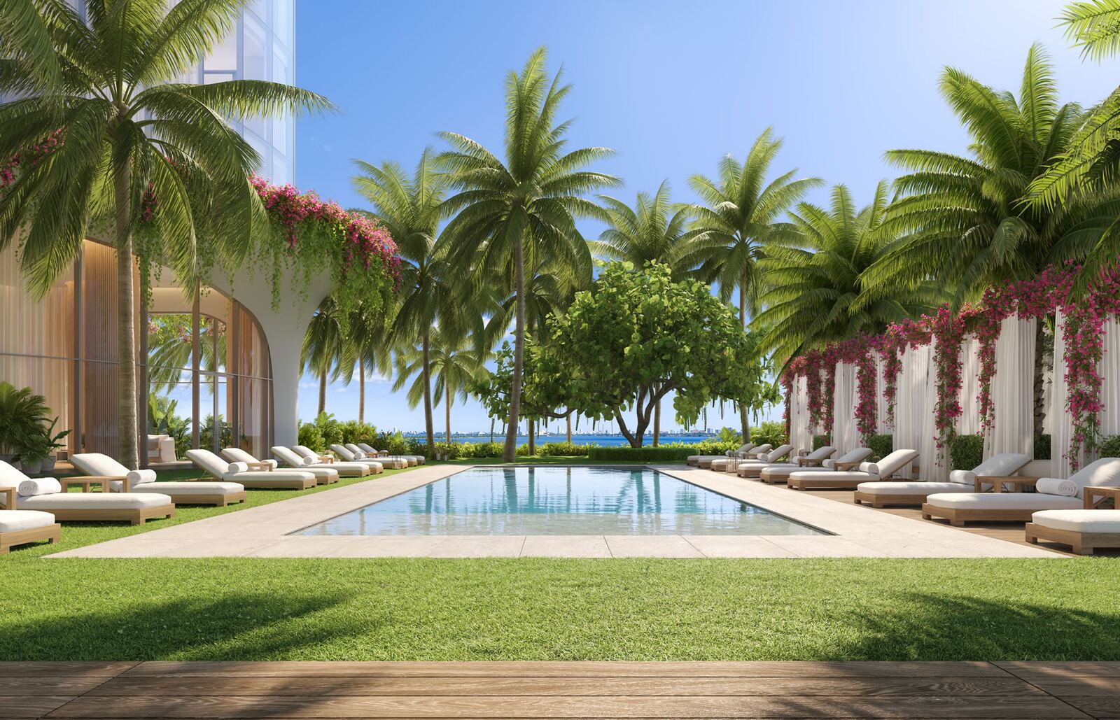 Piscina de jard&iacute;n enmarcada por palmeras y buganvillas con Biscayne Bay al fondo en EDITION Residences Miami Edgewater