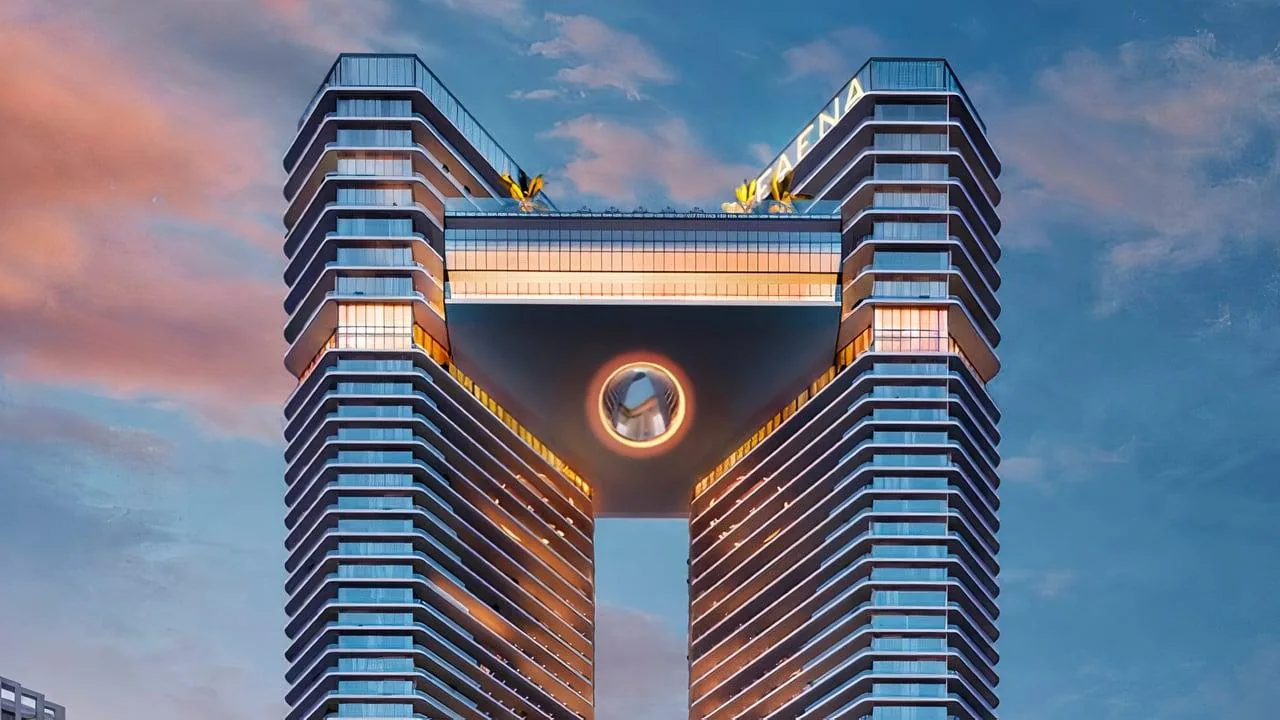 Render artístico de los pisos superiores de las dos torres de Faena Residences Miami y del puente elevado que las conecta, iluminados al atardecer.