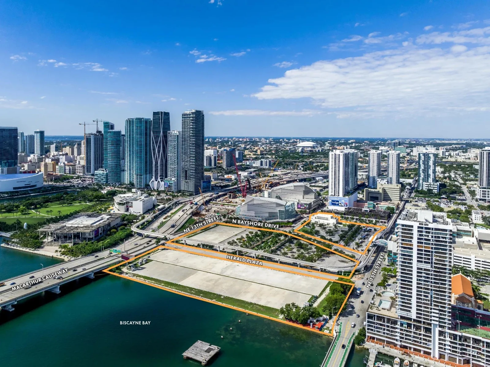 Aerial photograph of the vacant former Miami Herald waterfront site at 1431 N. Bayshore Drive in Miami, with the marketed parcel boundary outlined and the MacArthur Causeway and Biscayne Bay visible