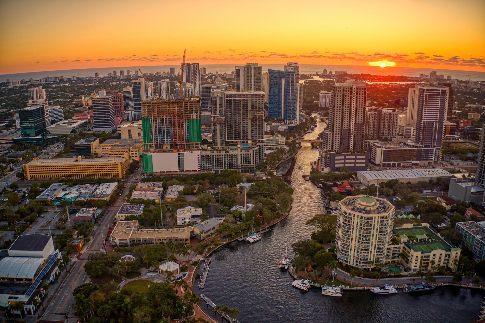 Aerial view of the downtown Fort Lauderdale skyline at sunset, with luxury high-rises, the New River, and the Intracoastal Waterway leading to the ocean