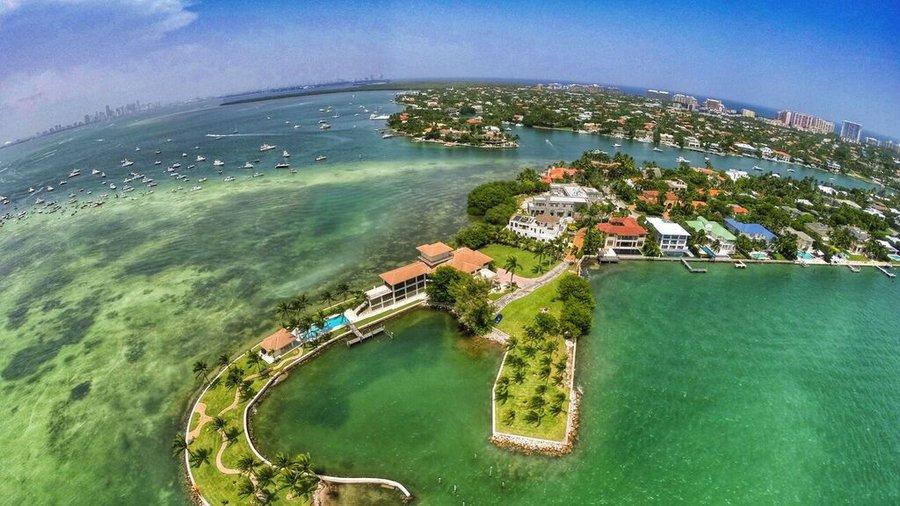 Vista a&eacute;rea de propiedades de lujo frente al agua con muelles privados y el horizonte de Miami al fondo en Key Biscayne, Florida
