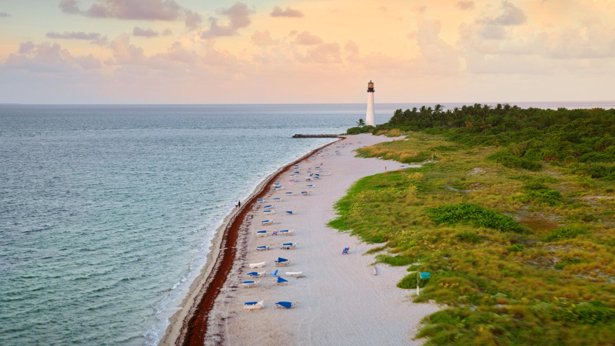 El hist&oacute;rico faro de Cape Florida y la playa de arena blanca del Parque Estatal Bill Baggs Cape Florida al atardecer en Key Biscayne, Florida