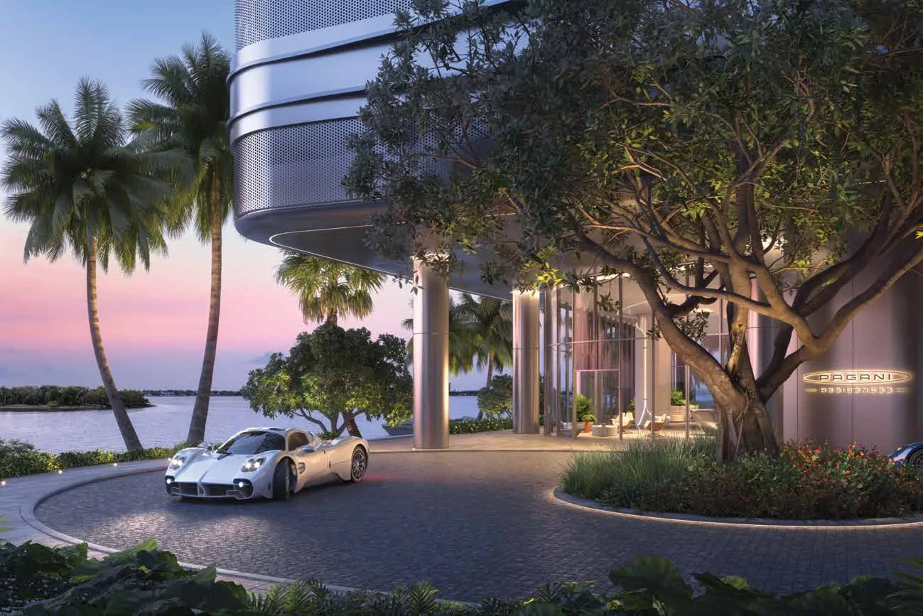 Representación conceptual del artista del porte-cochère de llegada frente al agua en Pagani Residences al atardecer, con el podio escultórico, palmeras y Biscayne Bay al fondo