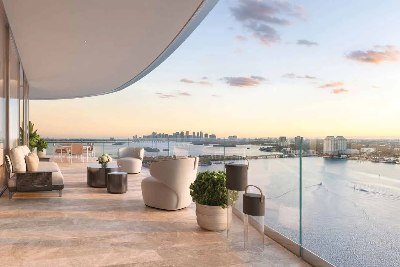 Representación conceptual del artista de una terraza en Pagani Residences al atardecer, con pisos de travertino, mobiliario de exterior y vista abierta sobre Biscayne Bay hacia el perfil de Miami