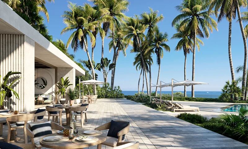 Terraza de comedor para residentes junto a la piscina bajo las palmeras frente al mar en The Perigon Miami Beach