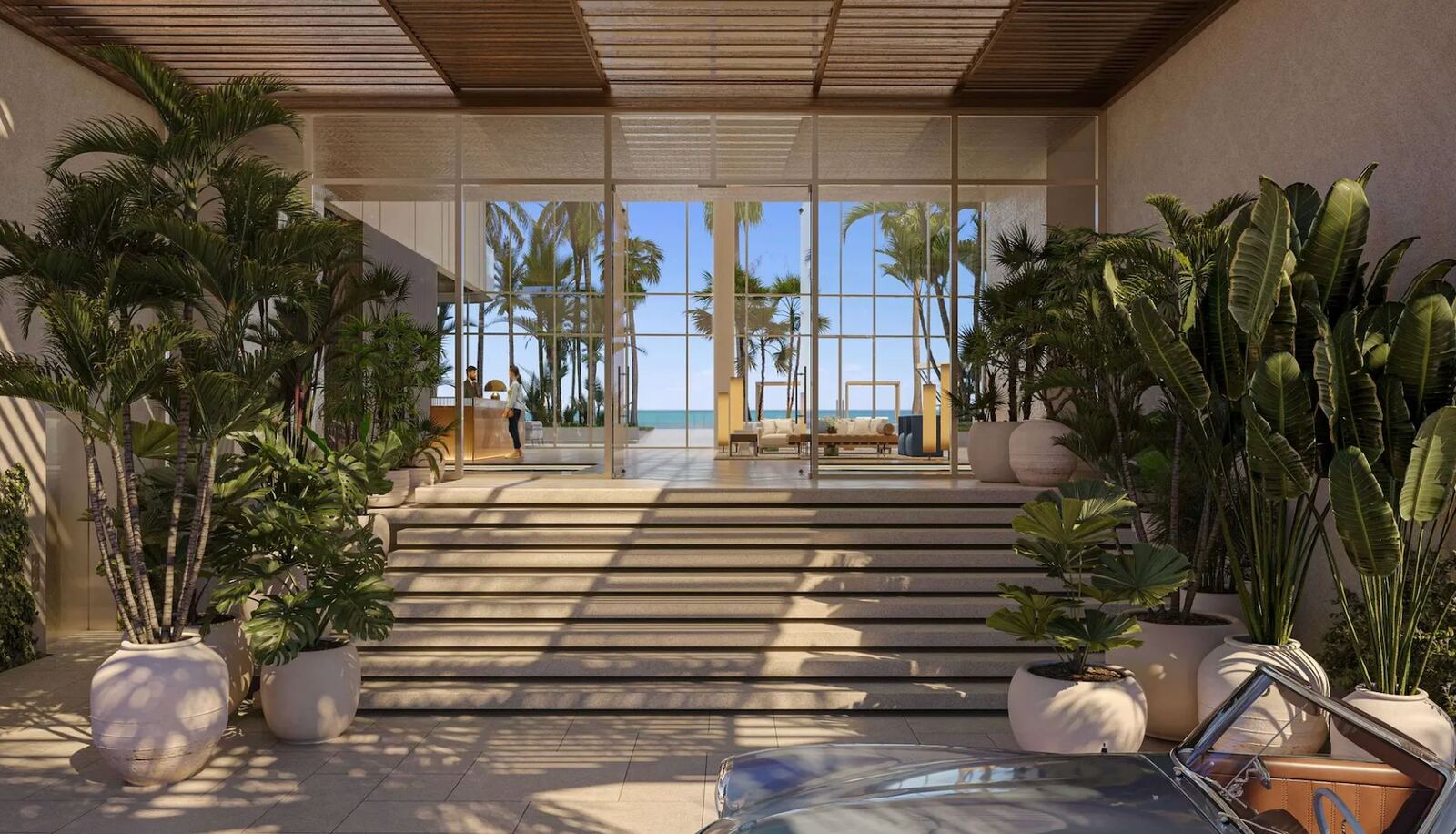 Escalinata de llegada entre palmeras hacia un lobby de cristal con el oc&eacute;ano Atl&aacute;ntico al fondo en The Ritz-Carlton Residences Pompano Beach