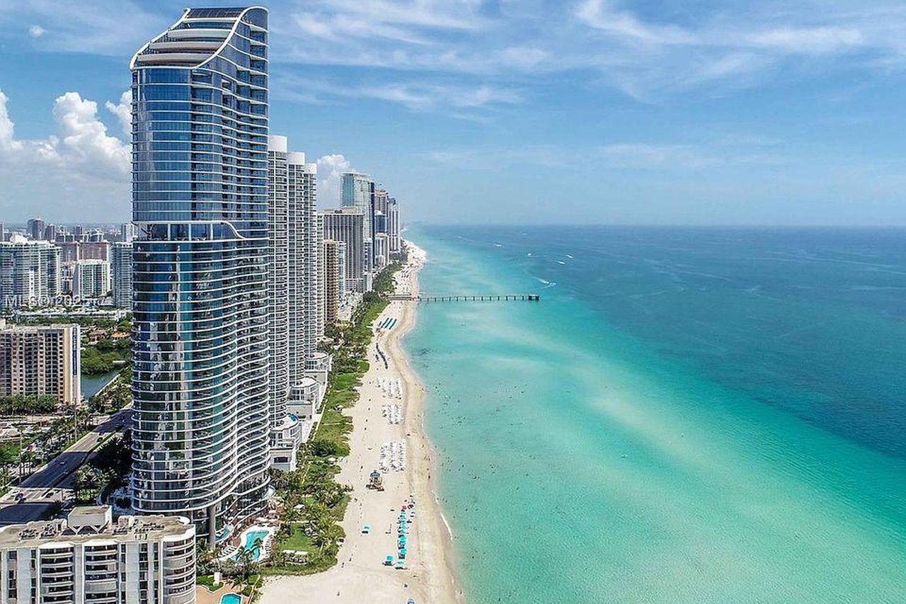 Torre de condominios de lujo frente al mar sobre el Atl&aacute;ntico turquesa y la playa en Sunny Isles Beach, Florida