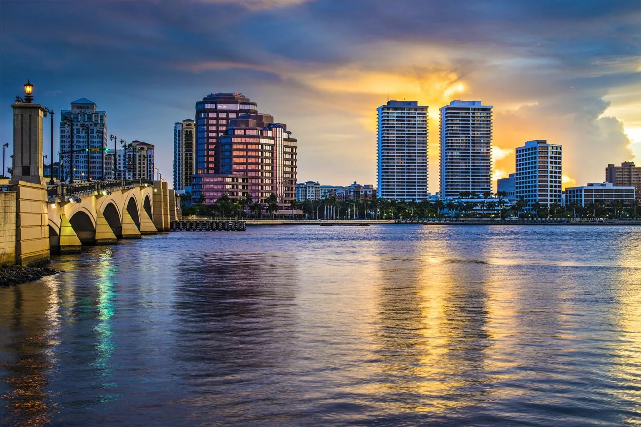 Downtown West Palm Beach skyline and waterfront towers along the Intracoastal Waterway at dusk, near the Flagler Memorial Bridge